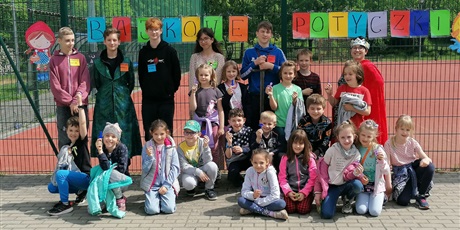 Powiększ grafikę: Grupa dzieci pozująca do zdjęcia na tle napisu Bajkowe potyczki.